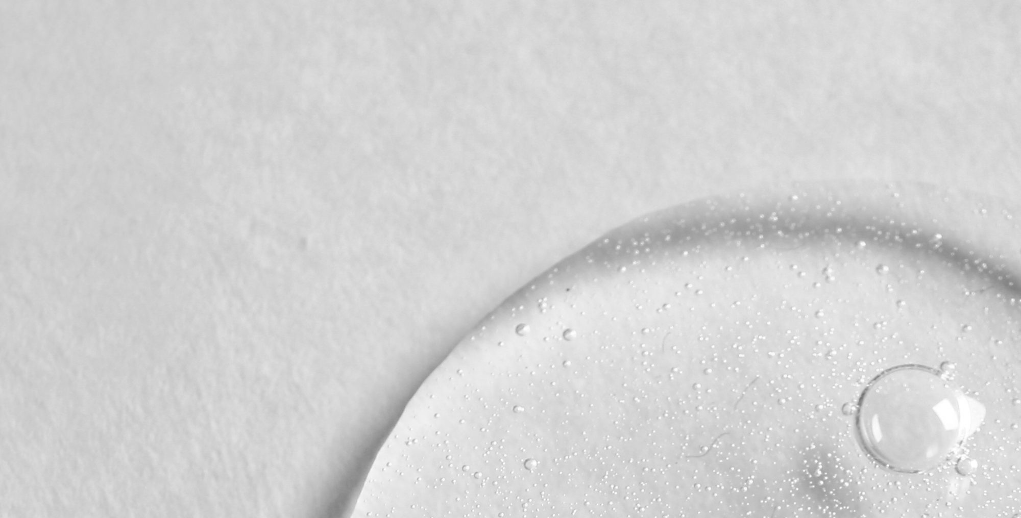 Close-up of a clear liquid droplet on a textured gray surface