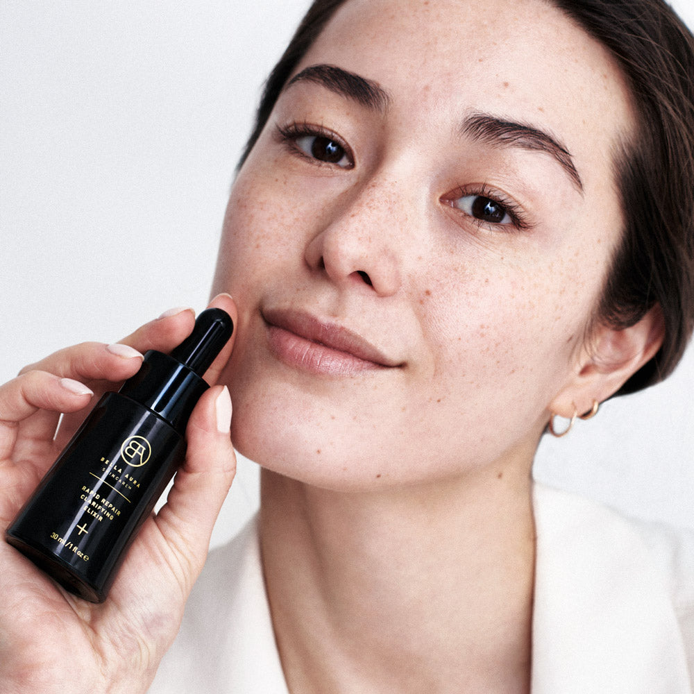 woman with bella aura skincare bottle