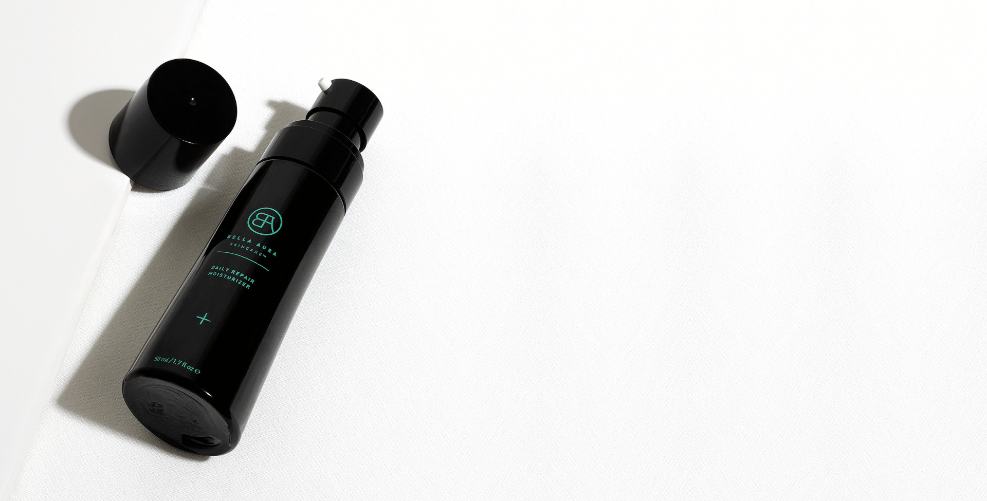 Black glass bottle bella aura daily repair moisturizer with a cap on a white background
