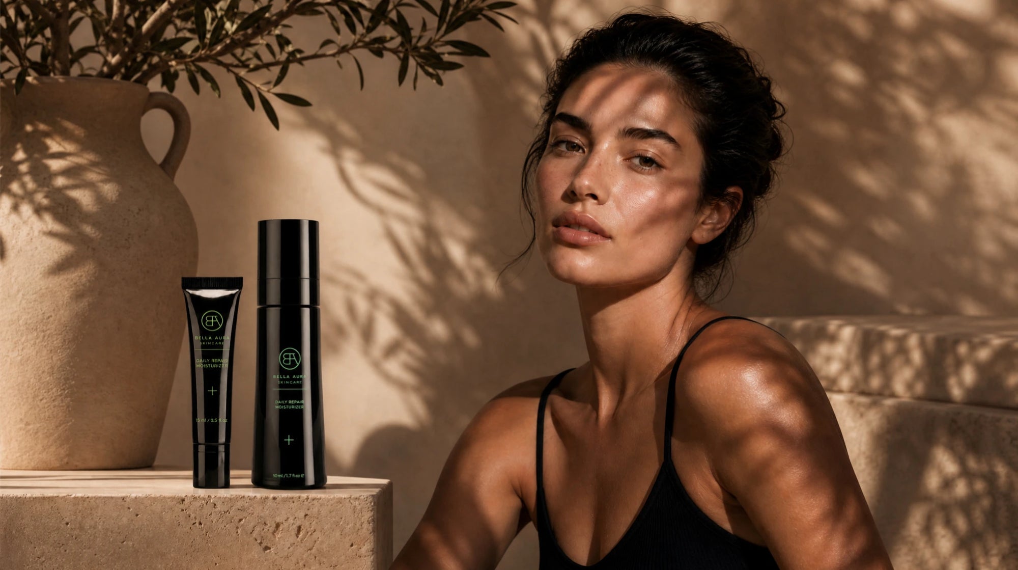Woman sitting next to bella aura skincare products with a natural setting